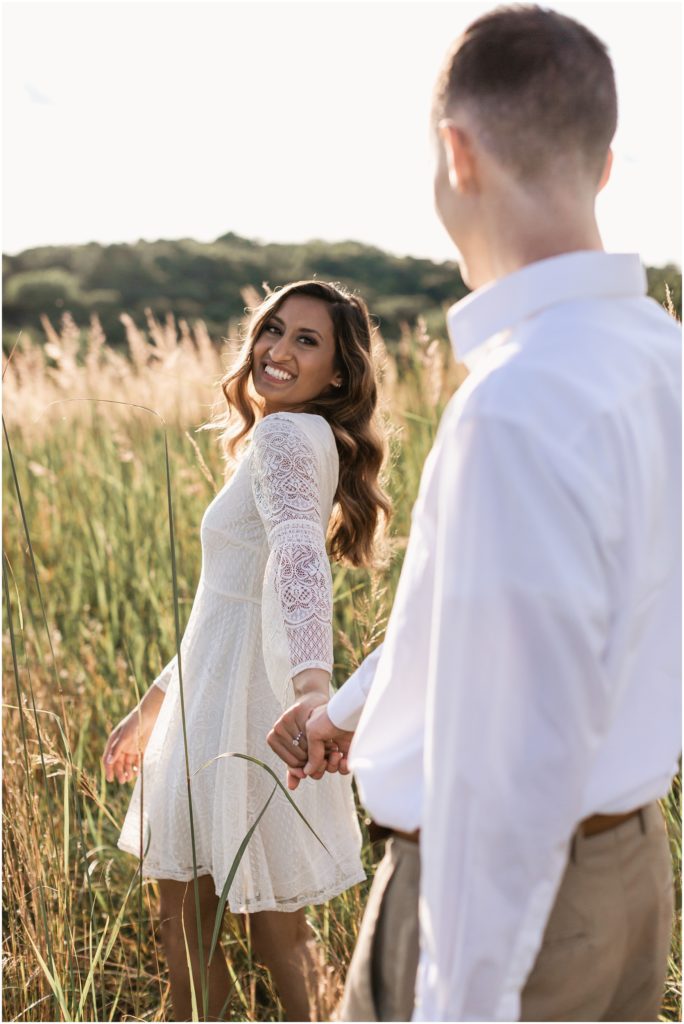 engaged couple wearing white in a field