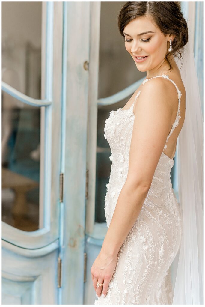 Bride smiles down at her wedding dress in the "getting ready" space at Bavaria Downs. 