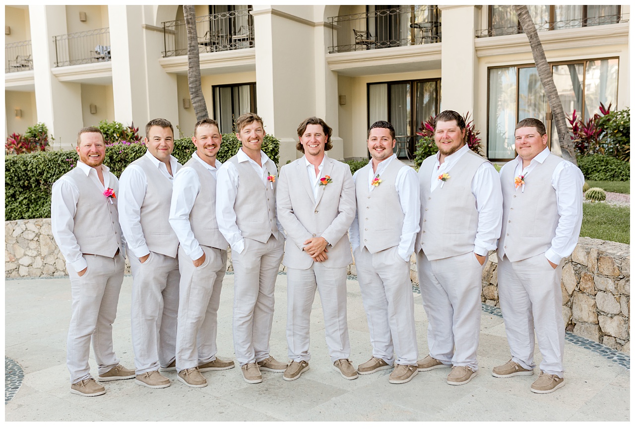 Groom and groomsmen stand for a portrait outside of Dreams Los Cabos. 