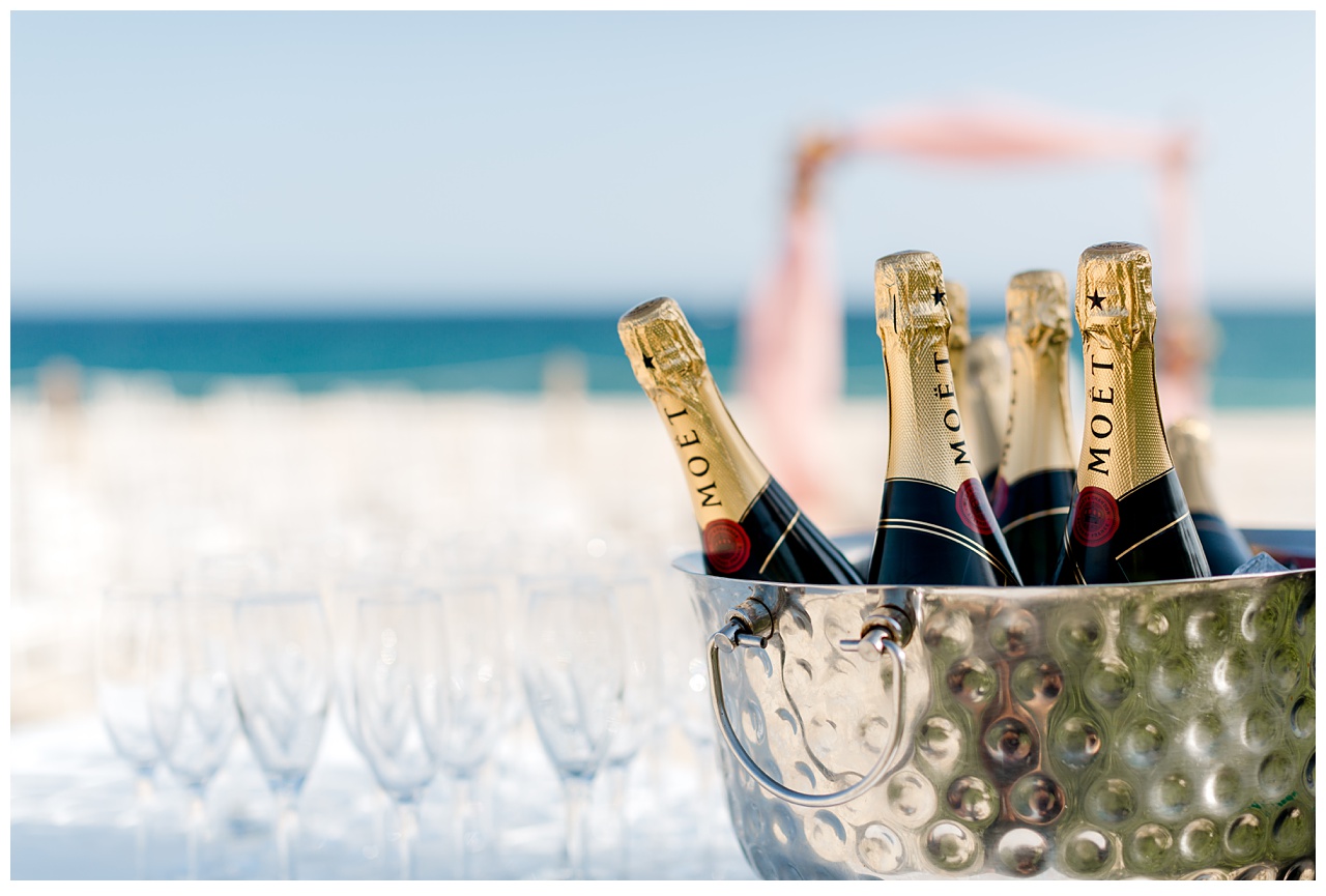 Champagne bottles sit in an ice bucket on a beach before destination wedding at Dreams Los Cabos. 