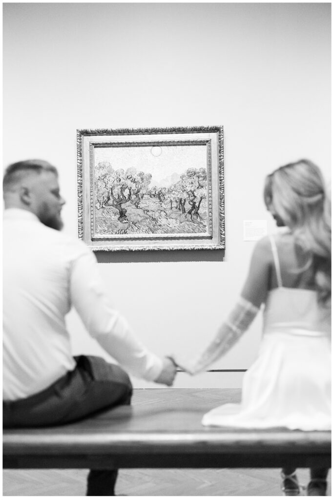 Couple hold hands in front of Van Gogh painting at Minneapolis Institute of Art during engagement photoshoot. 