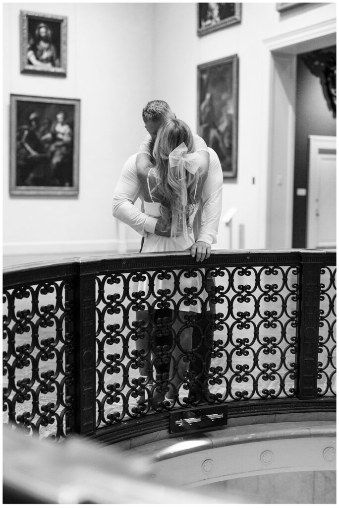 Couple kiss on balcony in front of paintings at the Minneapolis Institute of Art. 